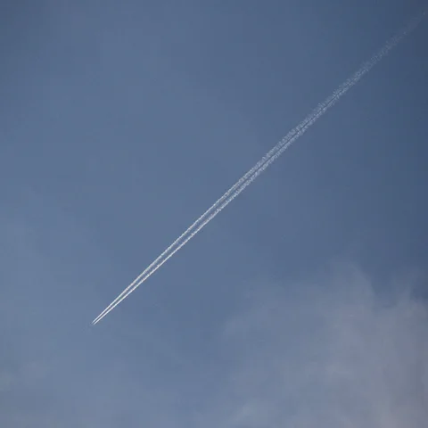 A contrail stretching diagonally across a blue sky